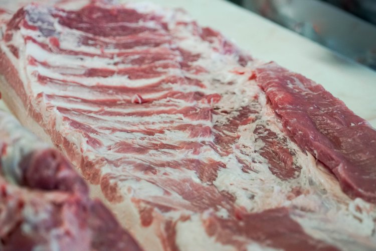 Close-up of fresh pork ribs showing layers of meat and fat, ideal for barbecuing or slow cooking.
